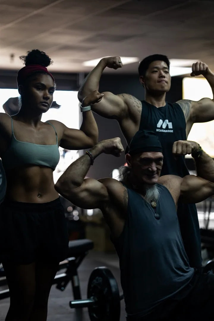Three people flexing and posing together in a gym