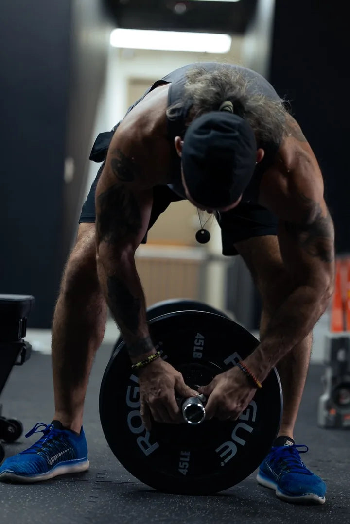 An athlete loading a weight plate onto a bar before the next set